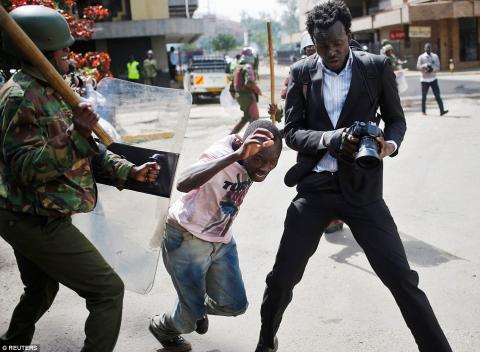 A Kenyan Military officer trying to hit a journalist with a big stick during 2017 presidential elections.